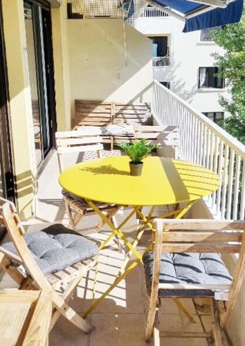 une table et des chaises jaunes sur un balcon dans l'établissement Gd Appartement climatisé, 5 personnes, 15 min a pied de la place de la Comédie, 15 min en voiture des plages, à Montpellier