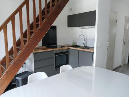 une cuisine avec une table blanche et un escalier dans l'établissement Appartement chaleureux., à Barcelonnette