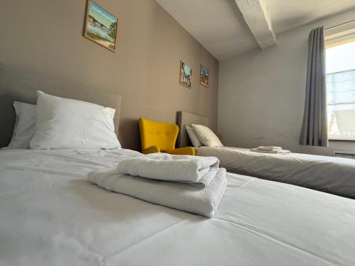a bedroom with two beds with white sheets and a yellow chair at Maison familiale et cosy à la mer in Saint-Valery-sur-Somme