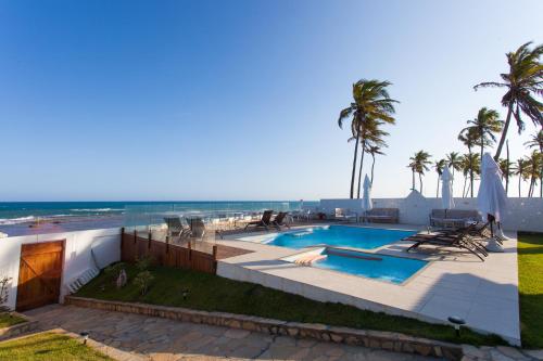 uma piscina com a praia ao fundo em Pousada a Capela em Arembepe