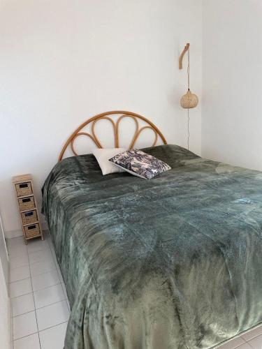 une chambre avec un grand lit avec une couverture verte dans l'établissement appartement face à la mer, piscine,parking,4couchages,clim, à La Celle-sous-Gouzon