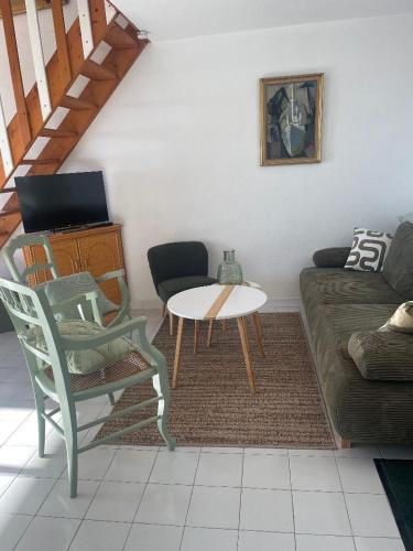 un salon avec un canapé, une table et une chaise dans l'établissement appartement face à la mer, piscine,parking,4couchages,clim, à La Celle-sous-Gouzon