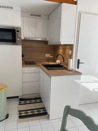 une cuisine avec des armoires blanches et un évier dans l'établissement appartement face à la mer, piscine,parking,4couchages,clim, à La Celle-sous-Gouzon