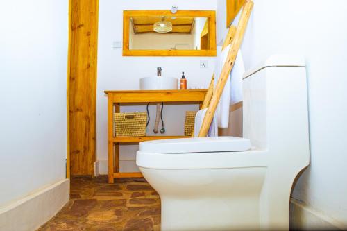 a bathroom with a white toilet and a wooden table at Akagera Park Inn in Akagera