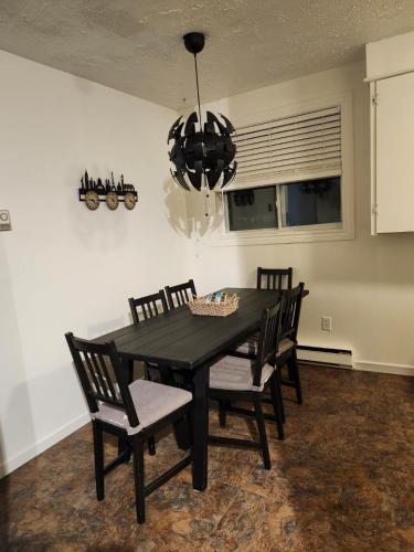 a black dining room table with chairs and a chandelier at 2 bedrooms house in Coldbrooke in Coldbrook