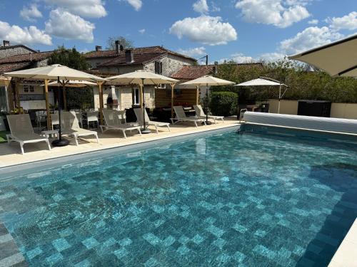 une piscine avec chaises et parasols dans l'établissement Chambre d'hôtes NATURISTE Le Jardin Des Hirondelles, à Blanzaguet-Saint-Cybard-le-Peyrat