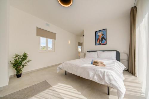 a white bedroom with a bed and a window at The Valley Collection - A25 - with Private hot tub in Xagħra
