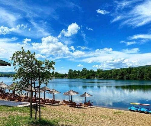 a beach with umbrellas and a body of water at Prenoćište Silver Lux Srebrno Jezero 11 in Veliko Gradište