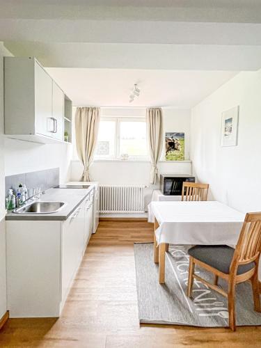 a kitchen with white cabinets and a table and a table and chairs at Hotel Bergstätter Hof in Immenstadt im Allgäu