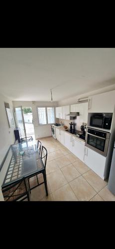 une cuisine avec une table en verre, une table et des chaises dans l'établissement Maisonnette rénovée avec cour, clim et métro à 5 min, à Marseille