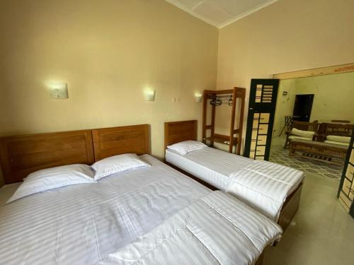 two twin beds in a bedroom with a mirror at D'Dalem Kadipaten Homestay in Yogyakarta