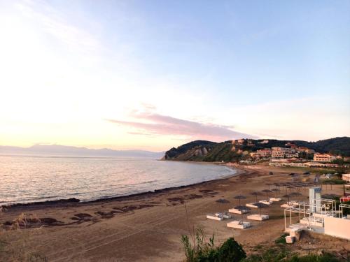 a beach with chairs and umbrellas and the ocean at Hotel Olga in Agios Stefanos