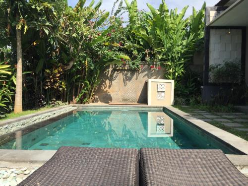 a swimming pool with a table and chairs in it at Ratna Villa in Ubud