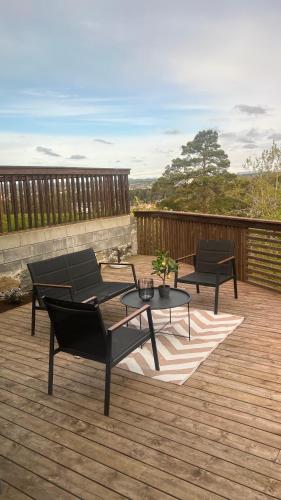 a patio with two chairs and a table on a deck at Moderne Leilighet med panorama utsikt in Sandefjord