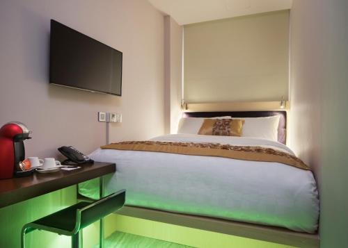 a bedroom with a bed and a desk with a phone at Hotel Clover 7 in Singapore