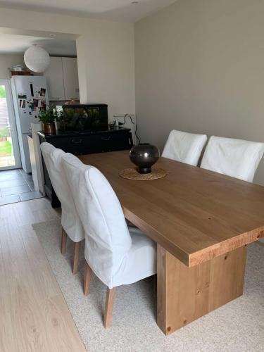 une table en bois avec des chaises blanches et une salle à manger dans l'établissement Petite maison de charme avec extérieur proche gare, à Laval