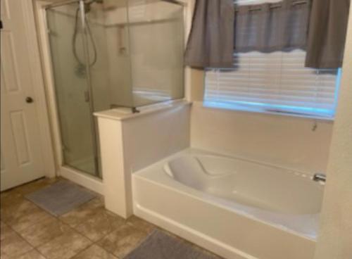 a white bathroom with a tub and a shower at Spacious 4 bedroom house! in Stockton