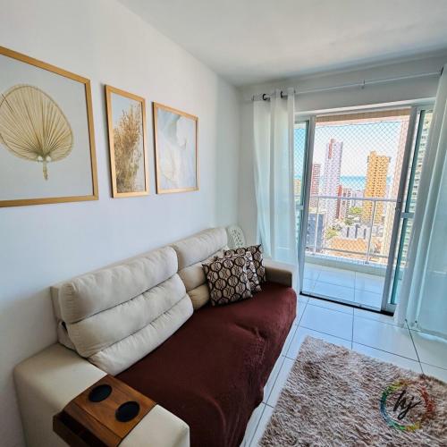 a living room with a couch and a large window at Fairmount 2102 in João Pessoa