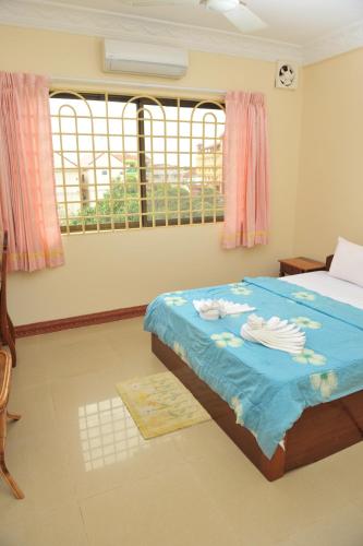 a bedroom with a bed with blue sheets and a window at Okay Guesthouse Siem Reap in Siem Reap