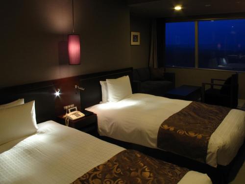 a hotel room with two beds and a couch at Hotel Epinard Nasu in Nasu