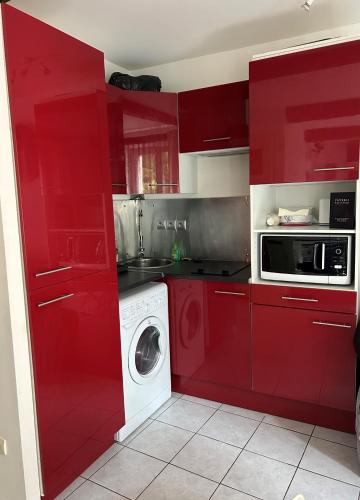 - une cuisine rouge avec un lave-linge et un four micro-ondes dans l'établissement Appartement-Studio, à Sérignan