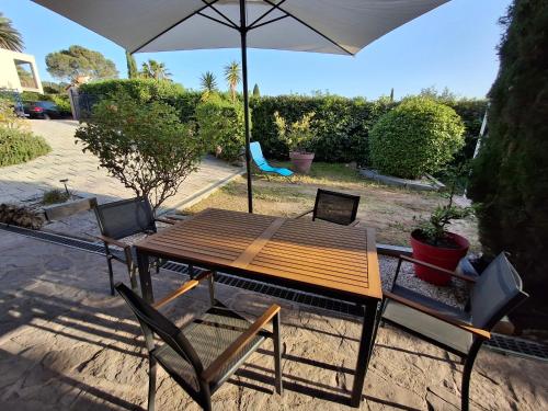 a wooden table with two chairs and an umbrella at Appt 83m2 rez de jardin dans villa parc privé balcon vue mer in Saint-Raphaël