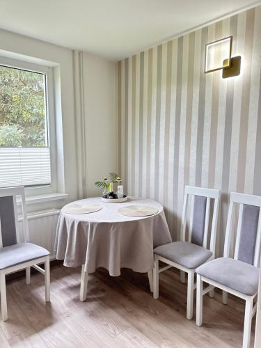 een witte tafel met twee stoelen en een tafel met bloemen erop bij LIUxSAU apartmentai in Mažeikiai