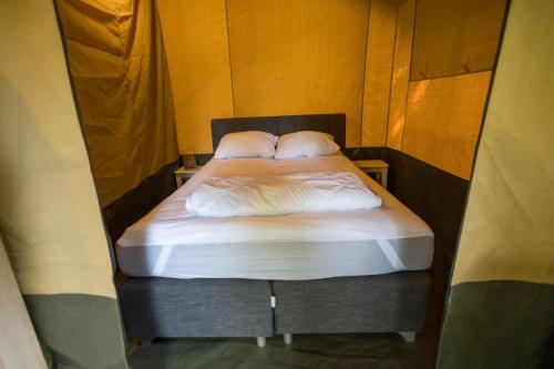 a bed with two pillows on it in a room at Luxe 5 persoons safaritent in Anna Paulowna