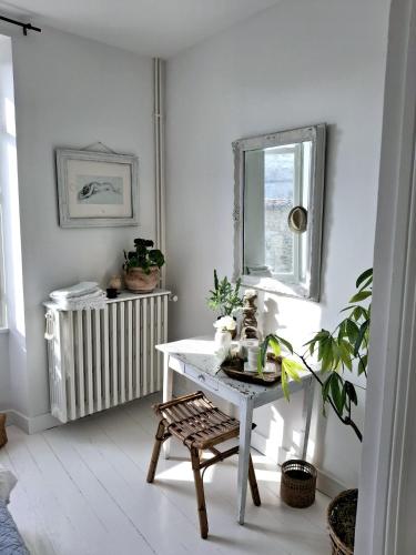 Cette chambre blanche dispose d'une table et d'une fenêtre. dans l'établissement La Maison Ânanda, à Aigre