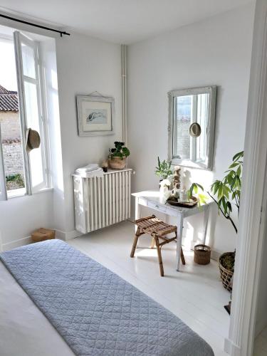 une chambre avec un lit, une table et des fenêtres dans l'établissement La Maison Ânanda, à Aigre