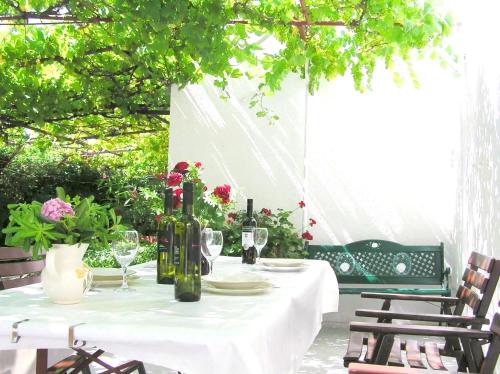 a white table with wine bottles and glasses on it at Holiday House Jure in Senj