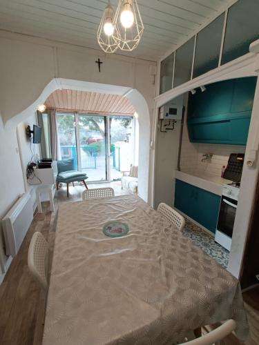 une salle à manger avec une grande table et une cuisine dans l'établissement maison Madeleine, à Saint-Gilles-Croix-de-Vie