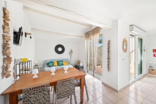 une salle à manger avec des murs blancs et une table en bois dans l'établissement La Capte idyllique- Hyères Plage T3 CLIM WIFI BY HC, à Hyères