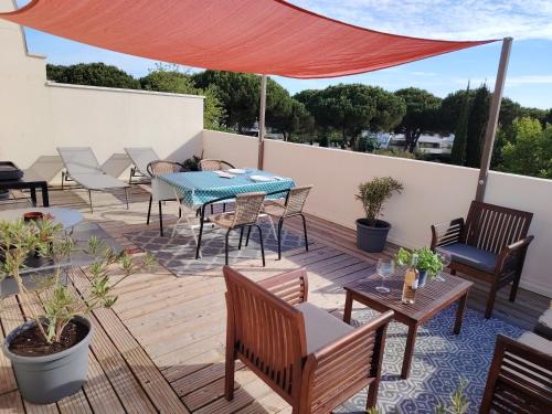 un patio avec des tables et des chaises et un auvent rouge dans l'établissement Appartement avec garage et grande terrasse , proximité des plages, à La Grande Motte