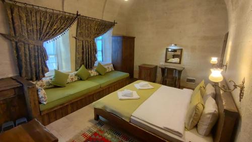 a bedroom with a bed and a couch and a window at ARMEsos Cave Hotel in Urgup