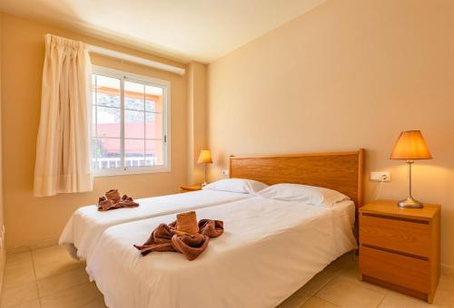 a bedroom with a large white bed with brown towels on it at Relax, descanso y una experiencia inolvidable in Costa Calma