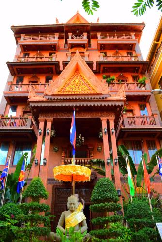 a woman sitting under an umbrella in front of a building at Okay Guesthouse Siem Reap in Siem Reap