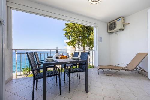 a dining room with a table and chairs on a balcony at Apartmani Heta Alagic I in Selce