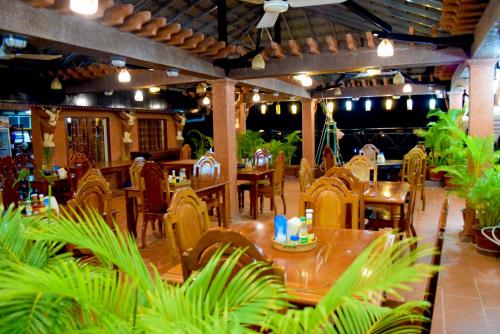 a restaurant with wooden tables and chairs and plants at Okay Guesthouse Siem Reap in Siem Reap