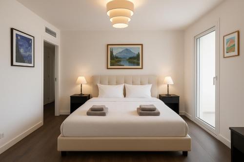 - une chambre blanche avec un grand lit blanc et deux lampes dans l'établissement Stunning 1 Bedroom Apartment 5 minutes to Monaco racetrack - Perfect for Grand Prix, à Beausoleil