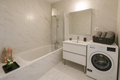 La salle de bains blanche est pourvue d'un lave-linge et d'une baignoire. dans l'établissement Stunning 1 Bedroom Apartment 5 minutes to Monaco racetrack - Perfect for Grand Prix, à Beausoleil
