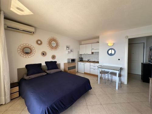 a bedroom with a bed and a table and a kitchen at Studio vue mer limitrophe à Monaco in Roquebrune-Cap-Martin