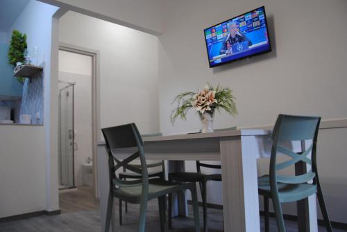 a dining room table with chairs and a tv on the wall at La Casetta al Poggio in Valentano