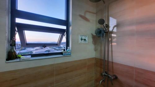 a bathroom with a shower with a window and a mirror at NEST House in Ấp Kim Thạch