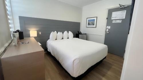 a large white bed in a hotel room at Colonial Hotel & Suites in Grand Bend
