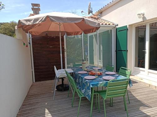 une table et des chaises avec un parasol sur une terrasse dans l'établissement Maison plage à 100 mètres et piste cyclable à 40 mètres, à Dolus-d'Oléron