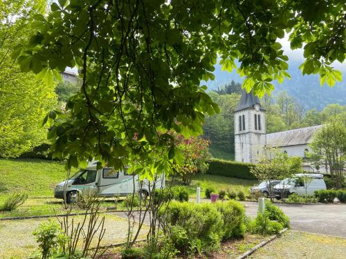 a church and cars parked in front of a yard at Camping les Marronniers in Glières-Val-de-Borne