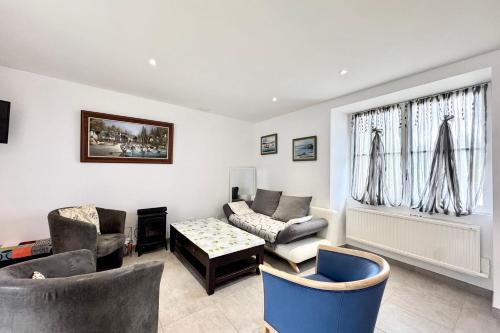 un salon avec un canapé, des chaises et une fenêtre dans l'établissement Maison de charme confort - Terrasse - Jardin, à Pont-Scorff