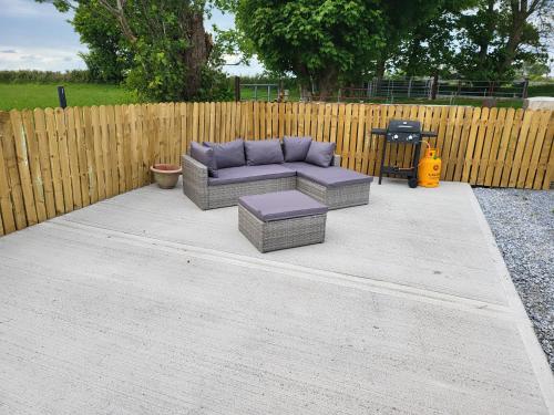 un patio avec un canapé, une table et une clôture dans l'établissement Peaceful Farm Cottage in Menlough near Mountbellew, Ballinasloe, Athlone & Galway, à Galway