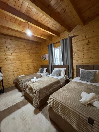 three beds in a room with wooden walls at Bujtina Miqesia in Theth